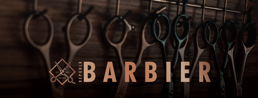 Barber scissors hanging in a row from a wall rack at Barbier, with the shop's name set across them.